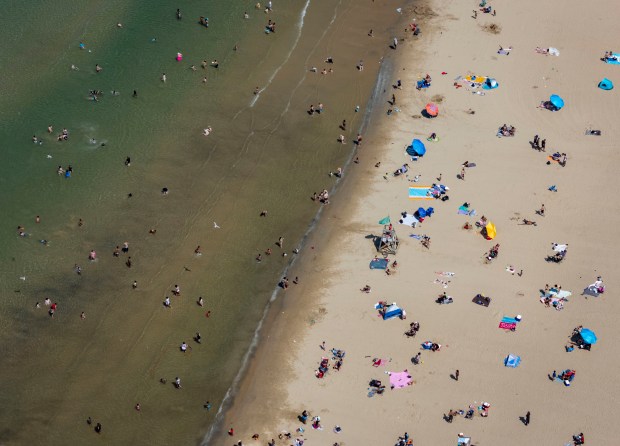 People relax on the sand and wade into the Lake...