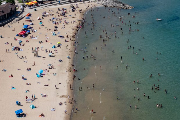 People relax on the sand and wade into the Lake...