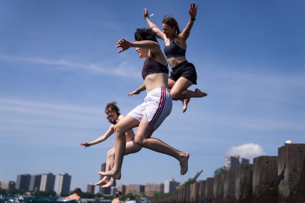 Maggie McDonough, center, jumps off the pier at Montrose Beach...