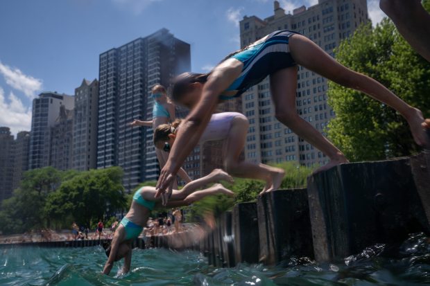 Emerson DeCamp, 10, right, dives in the water at the...