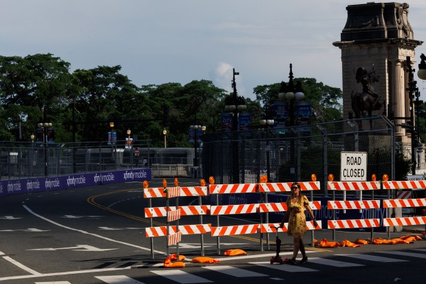 A person walks past barricades and scaffolding near East Congress Plaza Drive in preparation for the upcoming NASCAR Chicago Street Race scheduled for the 4th of July weekend, June 30, 2025. (Armando L. Sanchez/Chicago Tribune)