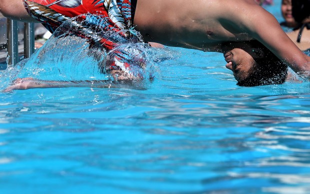 A boy tucks his head as he dives in the...