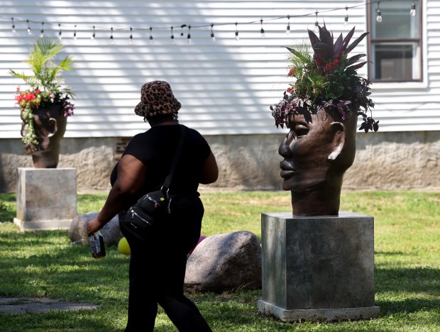 A woman gazes at sculptural planters created by artist Kenya Moffett-Garner, placed in a beautified vacant lot at the unBlocked Englewood block party in the 6500 block of South Aberdeen Street on June 28, 2025. (Chris Sweda/Chicago Tribune)