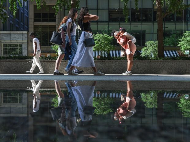 People walk past a puddle at the Daley Center, formed...