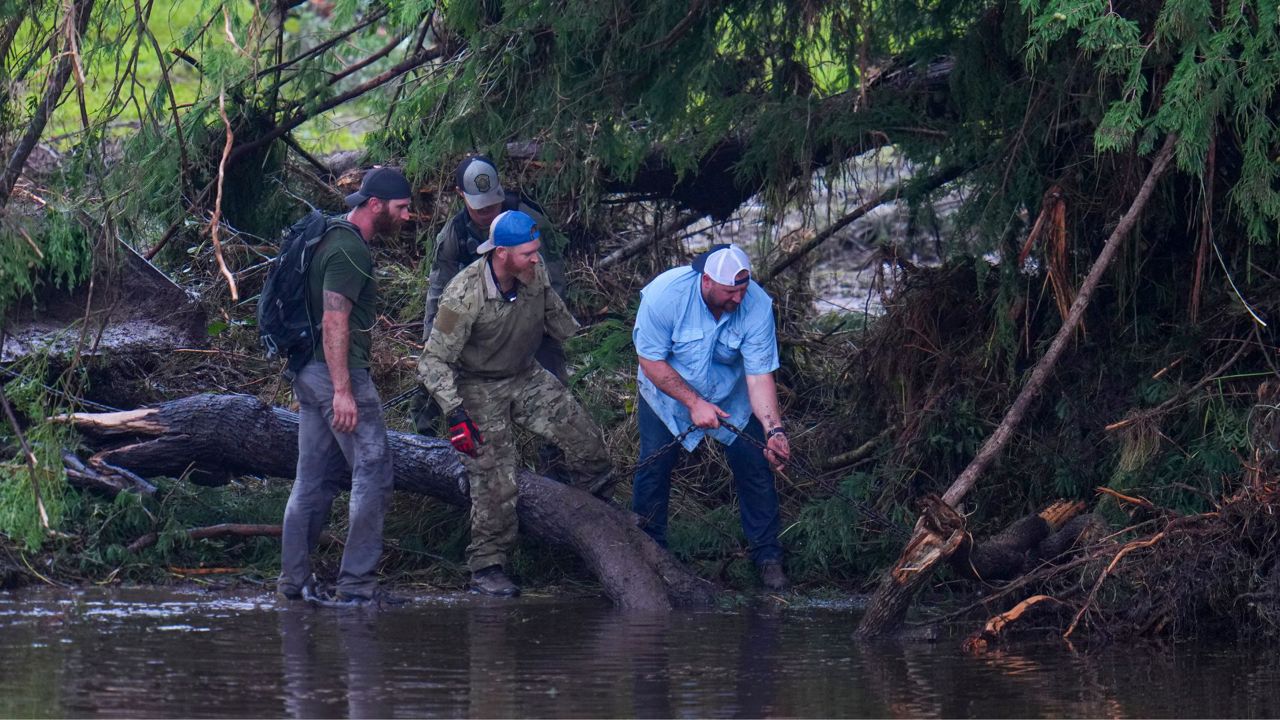 People remove debris from the Guadalupe River while inspecting an area at Camp Mystic, Sunday, July 6, 2025, in Hunt, Texas, after a flash flood swept through the area. (AP Photo/Julio Cortez)