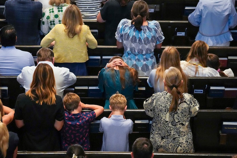Worshippers kneel as names submitted by the congregation for prayer are read during a vigil...