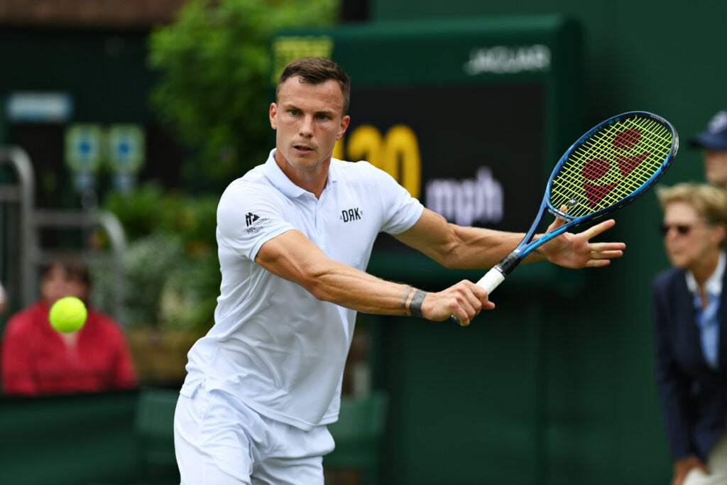 Marton Fucsovics of Hungary plays a backhand in his Men's Singles First Round match against Jannik Sinner of Italy during Day One of The Championships - Wimbledon 2021 at All England Lawn Tennis and Croquet Club.
