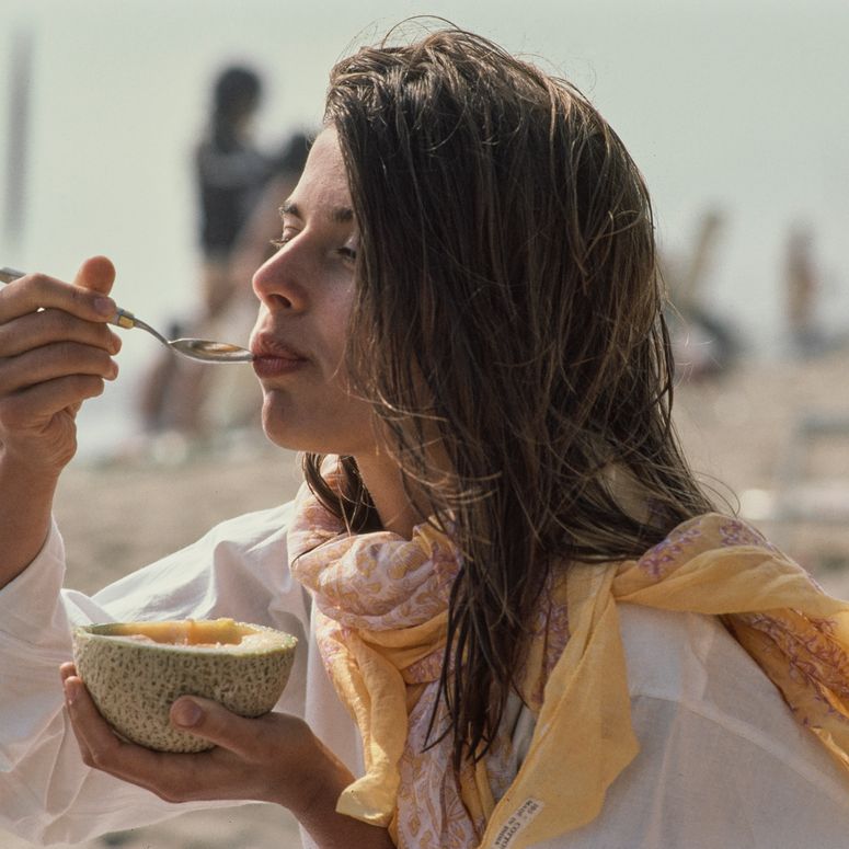 German fashion model and actress Nastassja Kinski, wearing a white shirt with a pink-and-yellow scarf, eating a melon in Los Angeles, California, June 1980. (Photo by Michael Ochs Archives/Getty Images)