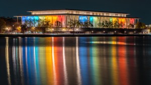 Reflected in the Potomac River, the exterior of the John F. Kennedy Center of the Performing Arts building (Credit: J. David Ake/Getty Images)