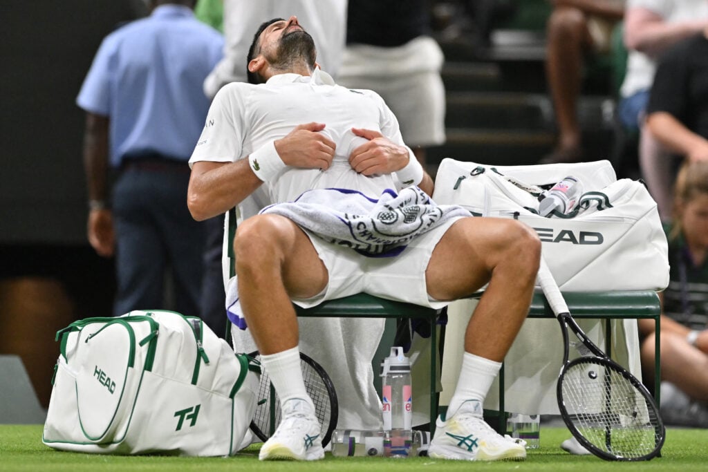 Novak Djokovic clutches his stomach.
