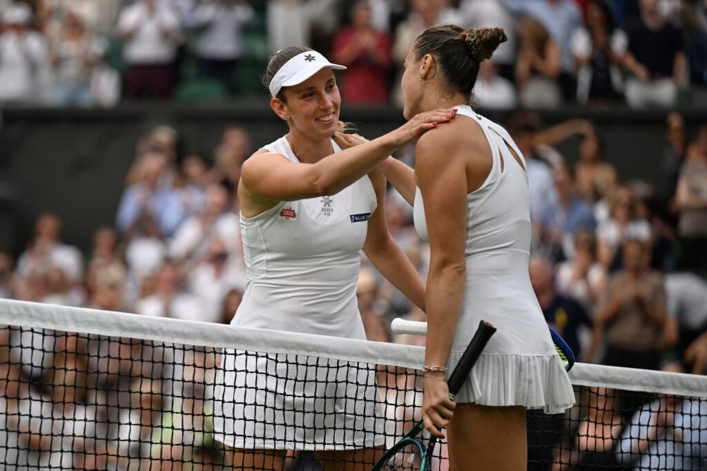 Aryna Sabalenka and Elise Mertens embrace at the net at Wimbledon 2025