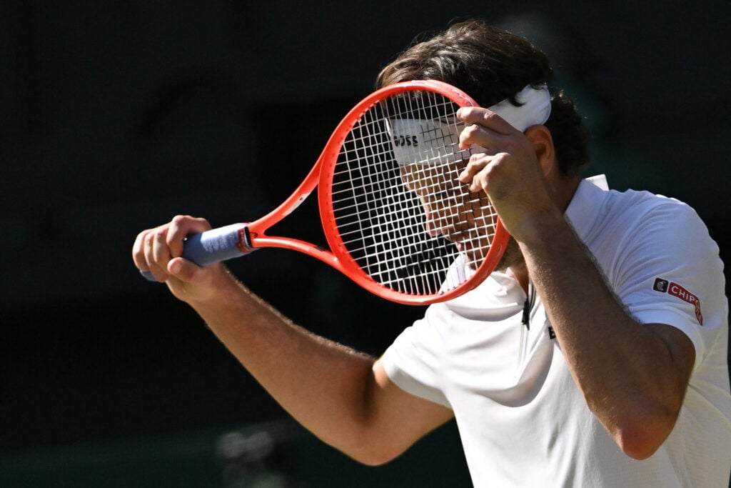 Taylor Fritz hides his head behind his racket.