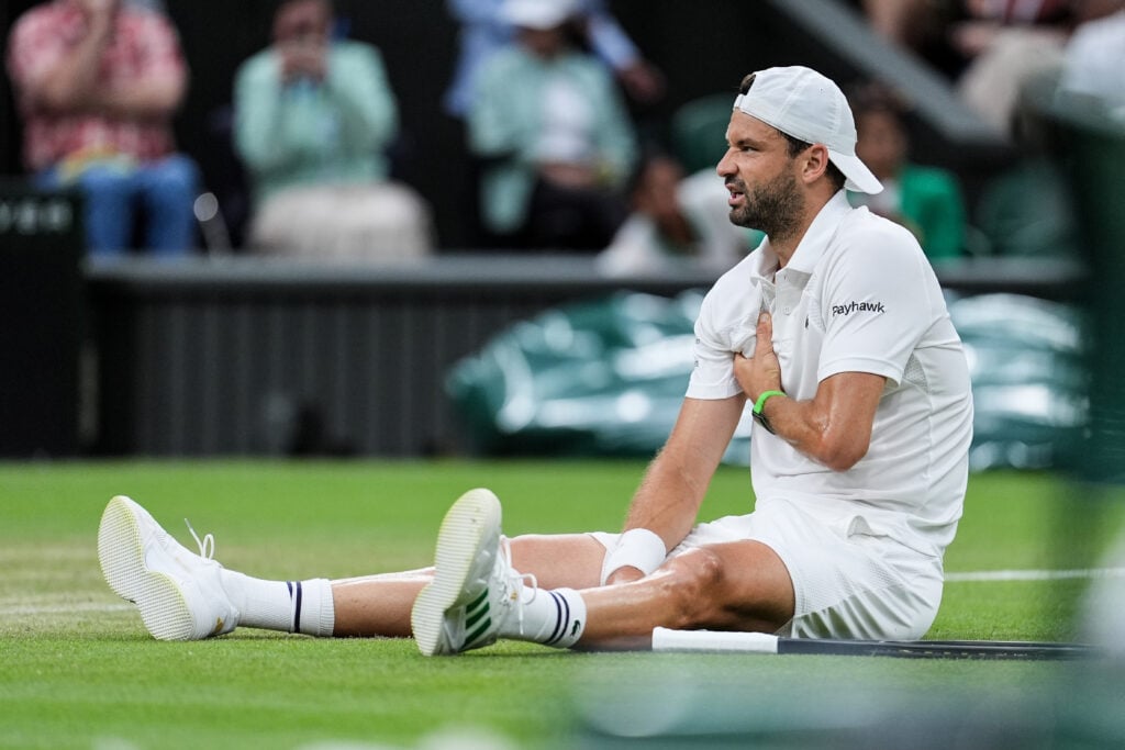 Grigor Dimitrov sits on the floor as he suffers an injury at Wimbledon in 2025