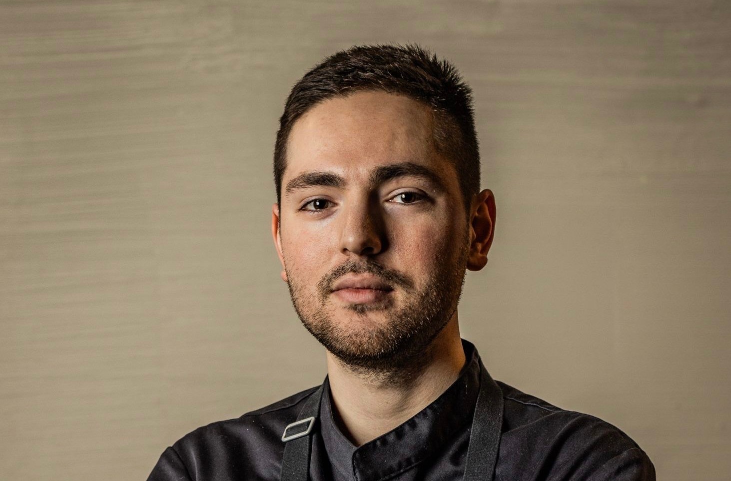 A chef smiling with hands folded.