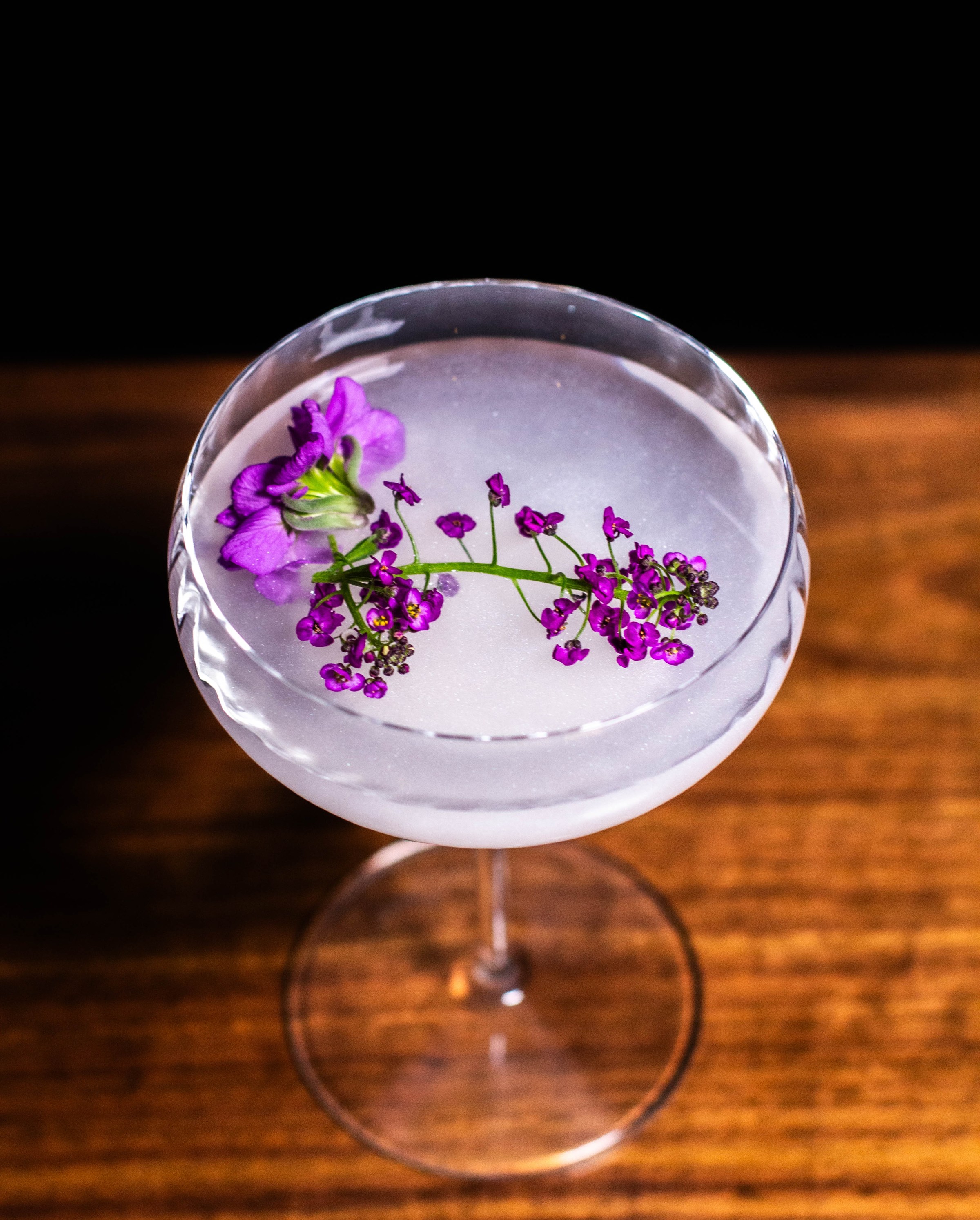 A coupe glass filled with a purple beverage.