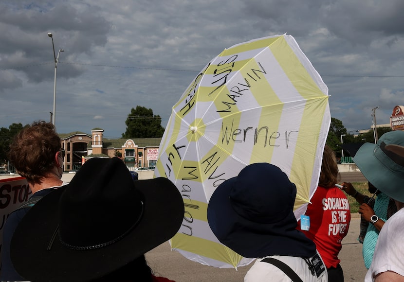 An umbrella bears the names of detainees as an event organizer read the names to a large...