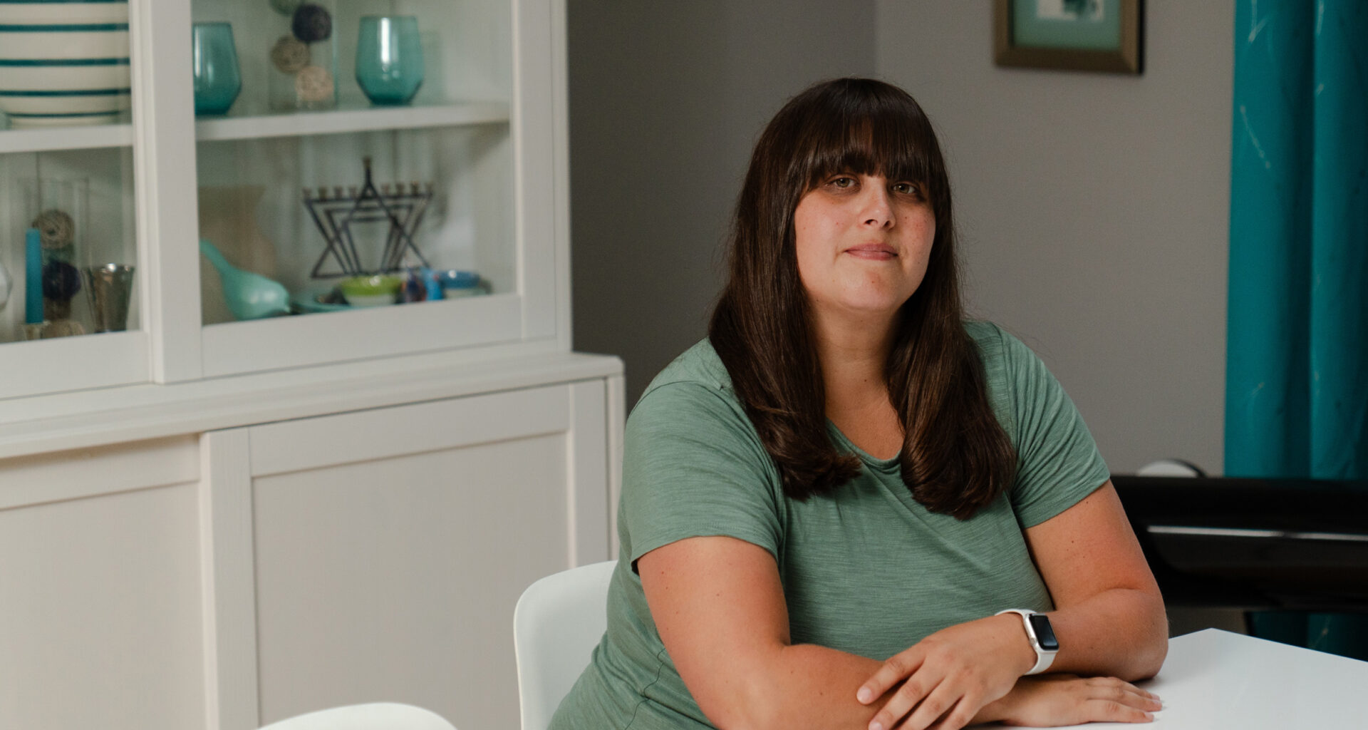 A portrait of a woman sitting at a dining room table.