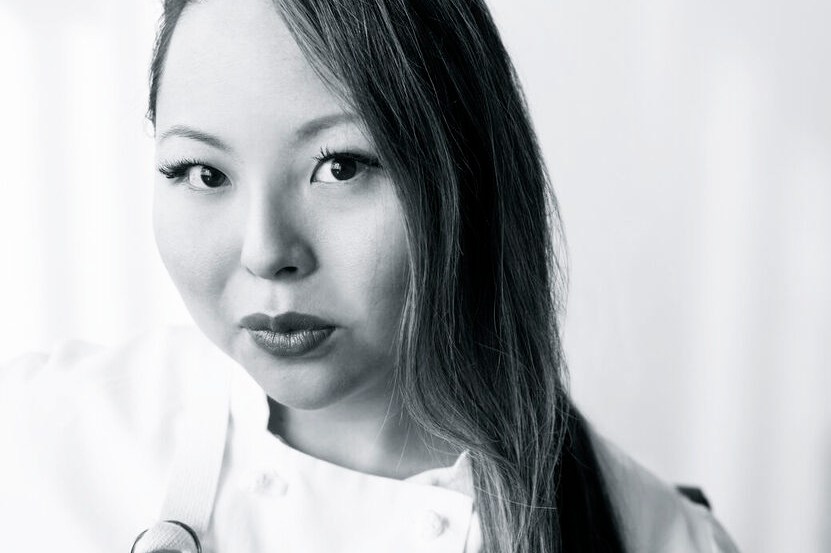 A black and white photo of a chef with long hair.