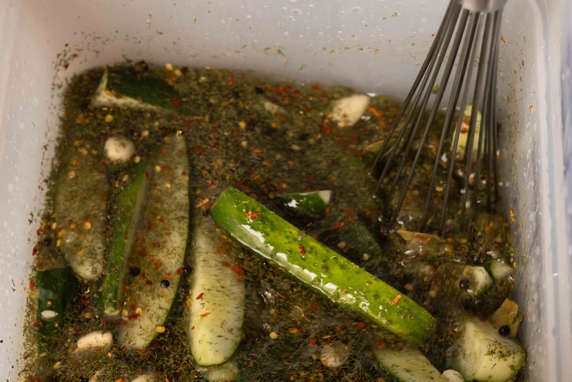Cucumbers sit in a vinegar bath seasoned with garlic, crushed red chilies, mustard seeds,...