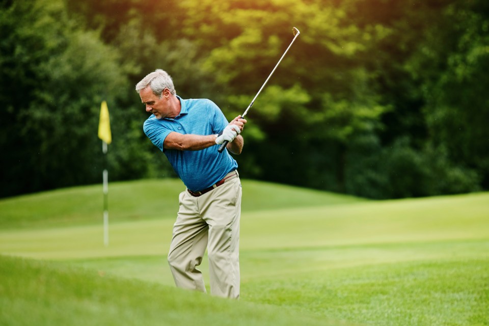A senior man golfing on a green course.