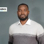 A man with a beard wearing a sweater and a collared shirt.