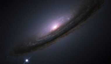 An oblique view of a spiral galaxy with a bright star next to it.