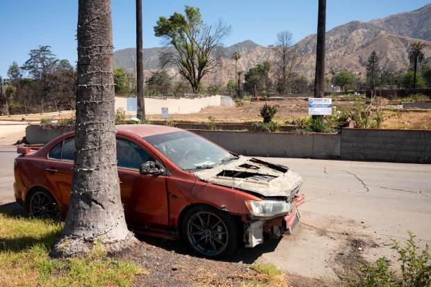 A burned out car still remains on the street in...