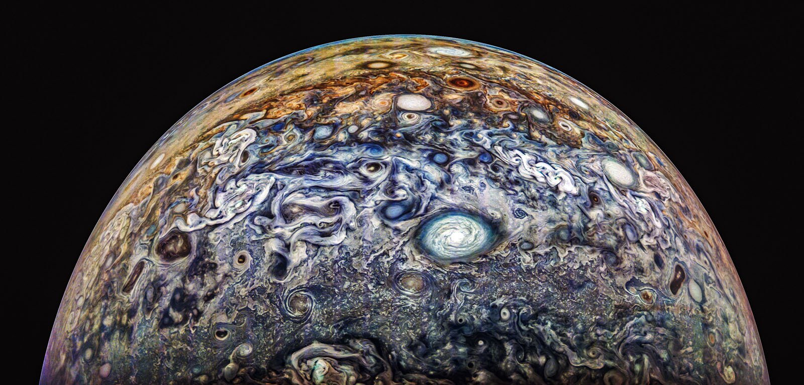 Colorful and swirling cloud patterns on Jupiter's atmosphere are shown, featuring a prominent white circular storm in the center, with various shades of blue, brown, and orange throughout the gaseous landscape under a dark sky.