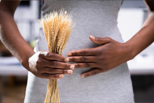 Hands on a stomach, with one holding wheat