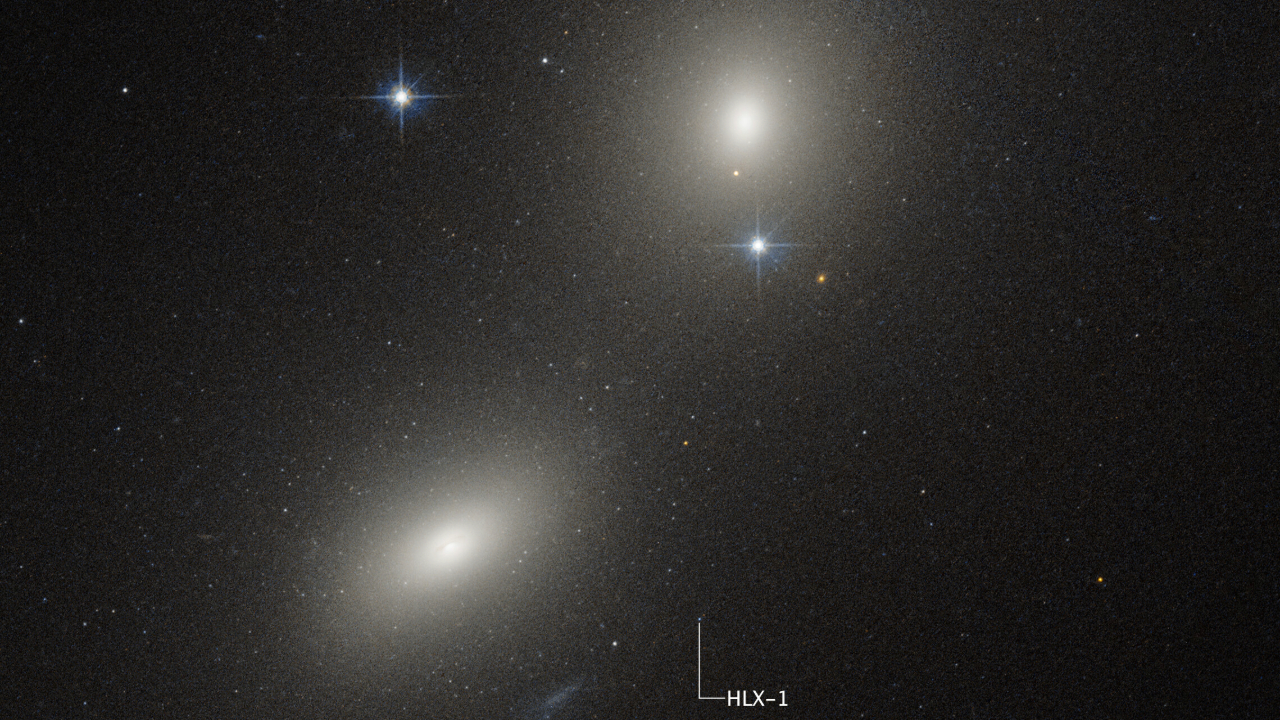 Three glowing lights illuminate the darkness of space with labels showing where a black hole is