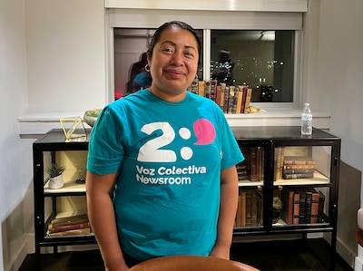 A photograph of a woman wearing a blue shirt posing for a photo in a room.
