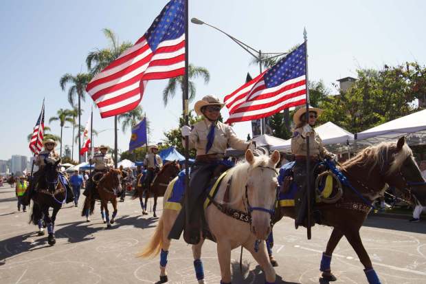 ....Escondido Mounted Posse officers ride horses with the flags of the United States during the parade at Orange Ave on Friday, July 4, 2025 in Coronado, CA. (Michael Ho / The San Diego Union-Tribune)