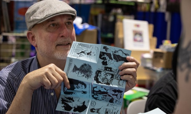 Jon Macy shows off a new comic he's been working on during Comic-Con at the Prism Comics table on Thursday, July 24, 2025 in San Diego, California. (Ana Ramirez / The San Diego Union-Tribune)