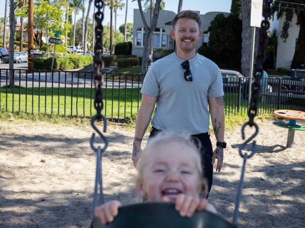 Sam Rodriguez, a lieutenant junior grade and medical corps officer for the U.S. Navy, pushes their child on a swing at a Kensington neighborhood park on Wednesday, July 2, 2025 in San Diego, California. (Ana Ramirez / The San Diego Union-Tribune)