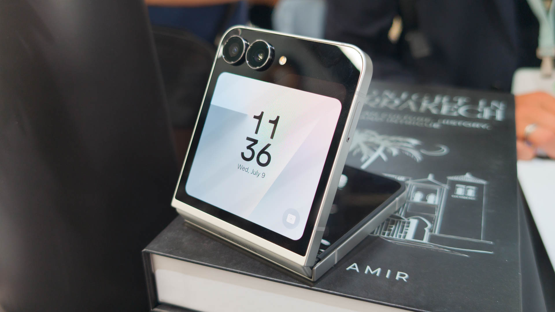 Samsung Galaxy Z Flip 7 FE in White partially unfolded on stack of books