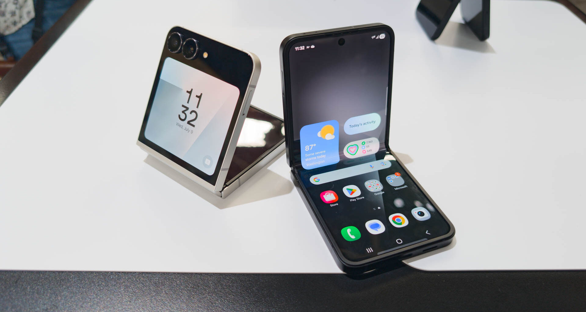 Samsung Galaxy Z Flip 7 FE in both Black and White colorways unfolded partially on table