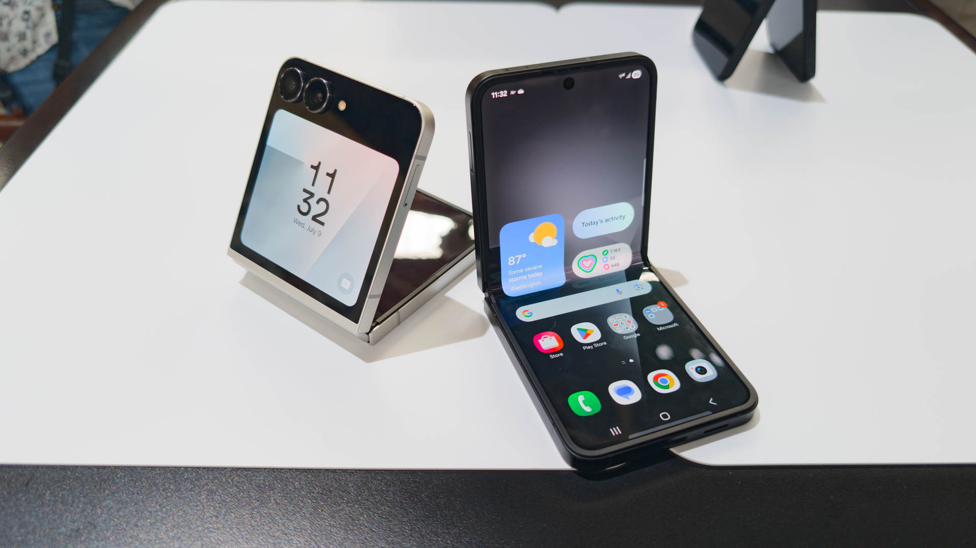 Samsung Galaxy Z Flip 7 FE in both Black and White colorways unfolded partially on table