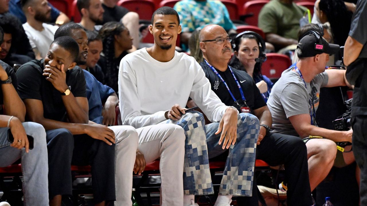 San Antonio Spurs' Victor Wembanyama, center, sits court side during the first half of an NBA summer league basketball game between the Spurs and Philadelphia 76ers, Thursday, July 10, 2025, in Las Vegas. (AP Photo/David Becker)