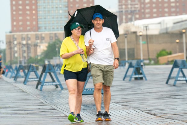 Heavy rains and strong winds passed through Coney Island resulting in people with umbrellas struggling against the wind and some beachgoers taking shelter, as others just took it in stride in Brooklyn on Sunday June 22, 2025. 1043. (Theodore Parisienne / New York Daily News)
