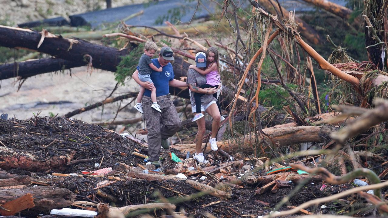 People climb over debris on a bridge atop the Guadalupe River after a flash flood swept through the area Saturday, July 5, 2025, in Ingram, Texas. (AP Photo/Julio Cortez)