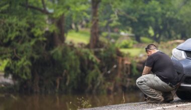 Avi Santos, 23, of San Antonio, Texas, reacts while stopping on the road alongside at Camp Mystic along the banks of the Guadalupe River after a flash flood swept through the area Sunday, July 6, 2025, in Hunt, Texas. (AP Photo/Julio Cortez)