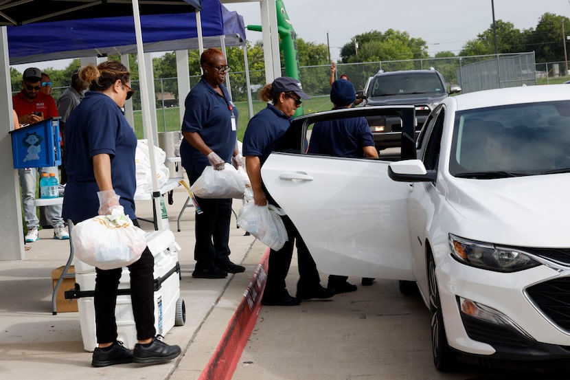Dallas Independent School District staff members load bags of food into a car on July 16,...