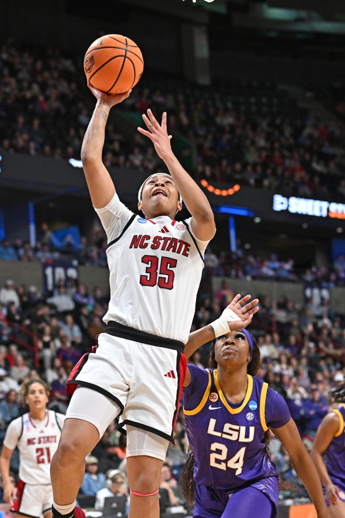 Zoe Brooks raises the ball over her head with her right hand and lifts her right foot as she starts a layup.