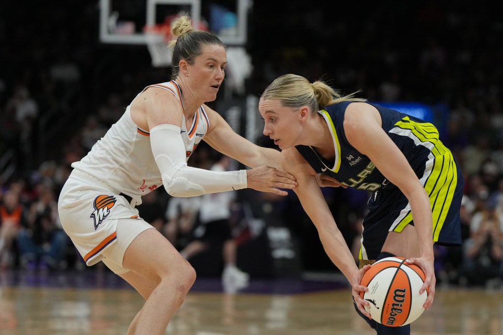 Phoenix Mercury guard Sami Whitcomb defends Paige Bueckers who bends over, holding the ball at her knee