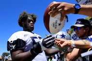 Dallas Cowboys guard Tyler Booker (52) signed autographs for fans following a training camp...