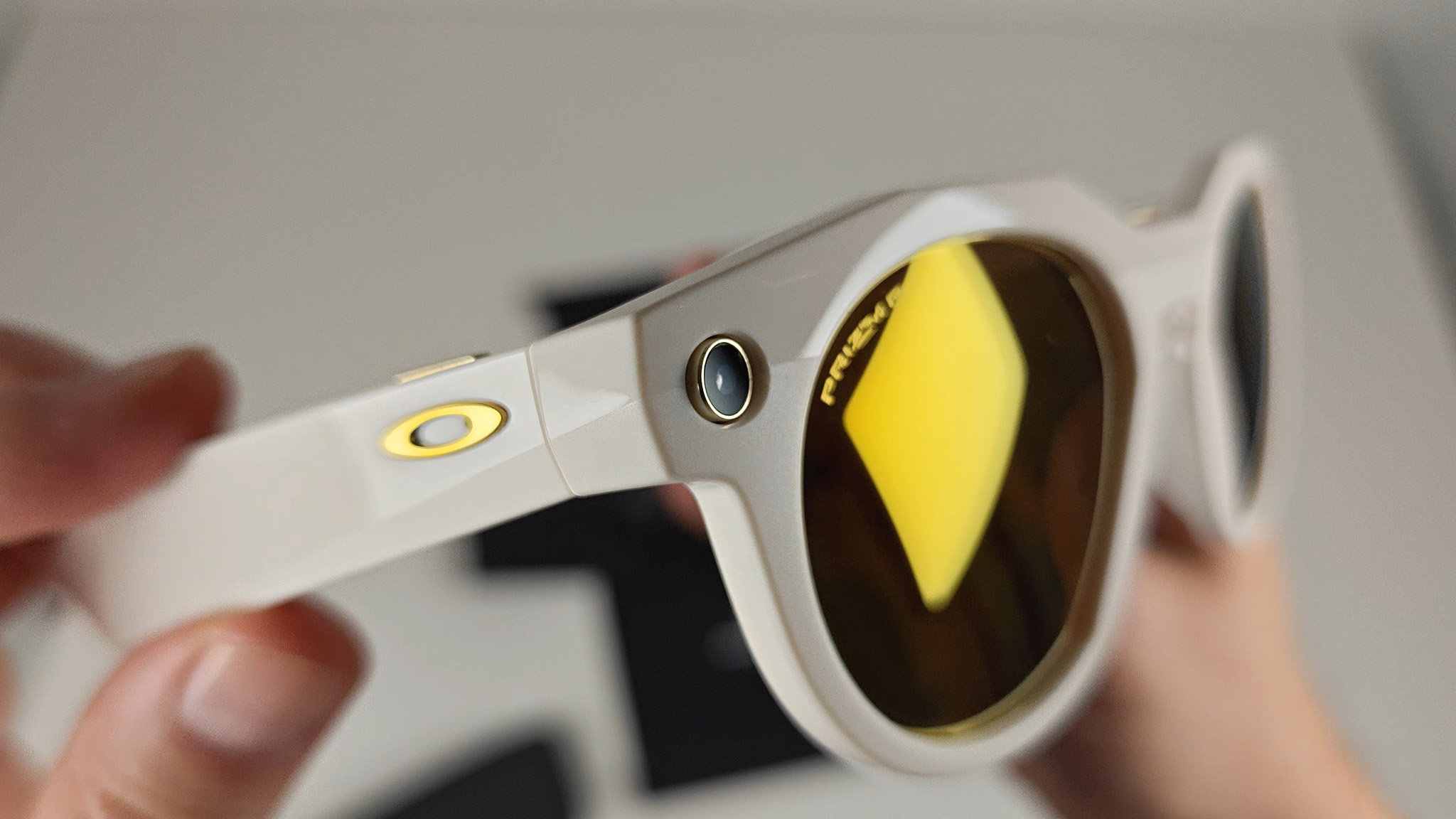 The gold-trimmed camera on the front of the limited edition warm white Oakley Meta HSTN smart glasses