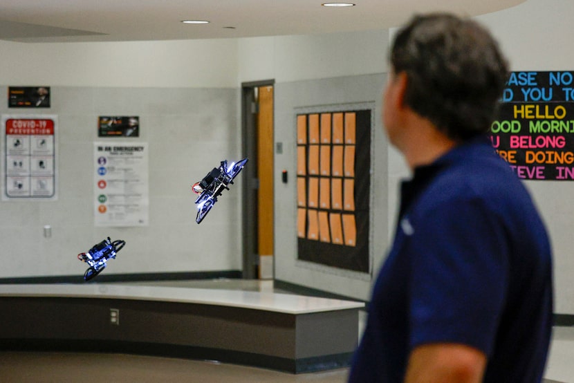 A Campus Guardian Angel employee watches as a pair of drones fly around during a...