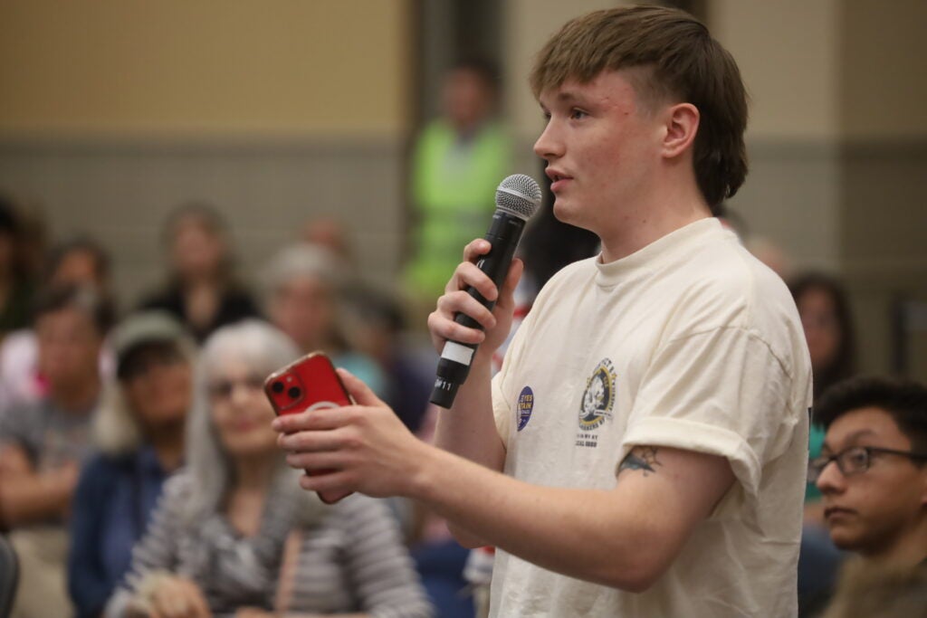 A college student holds a microphone while he asks a question to former U.S. Congressman Beto O'Rourke