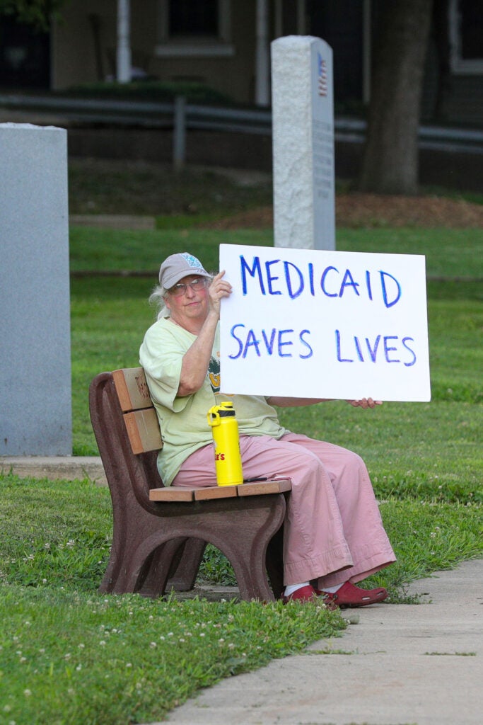 Woman holds placard during "Good Trouble Lives On: Dying for Healthcare" rally, Danville, PA, July 2025