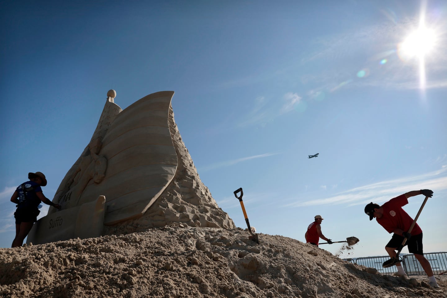 Sculptor Melineige Beauregard, left, worked on, “Revolutions Start Here,” the centerpiece of the 21st annual Revere Beach International Sand Sculpting Festival.